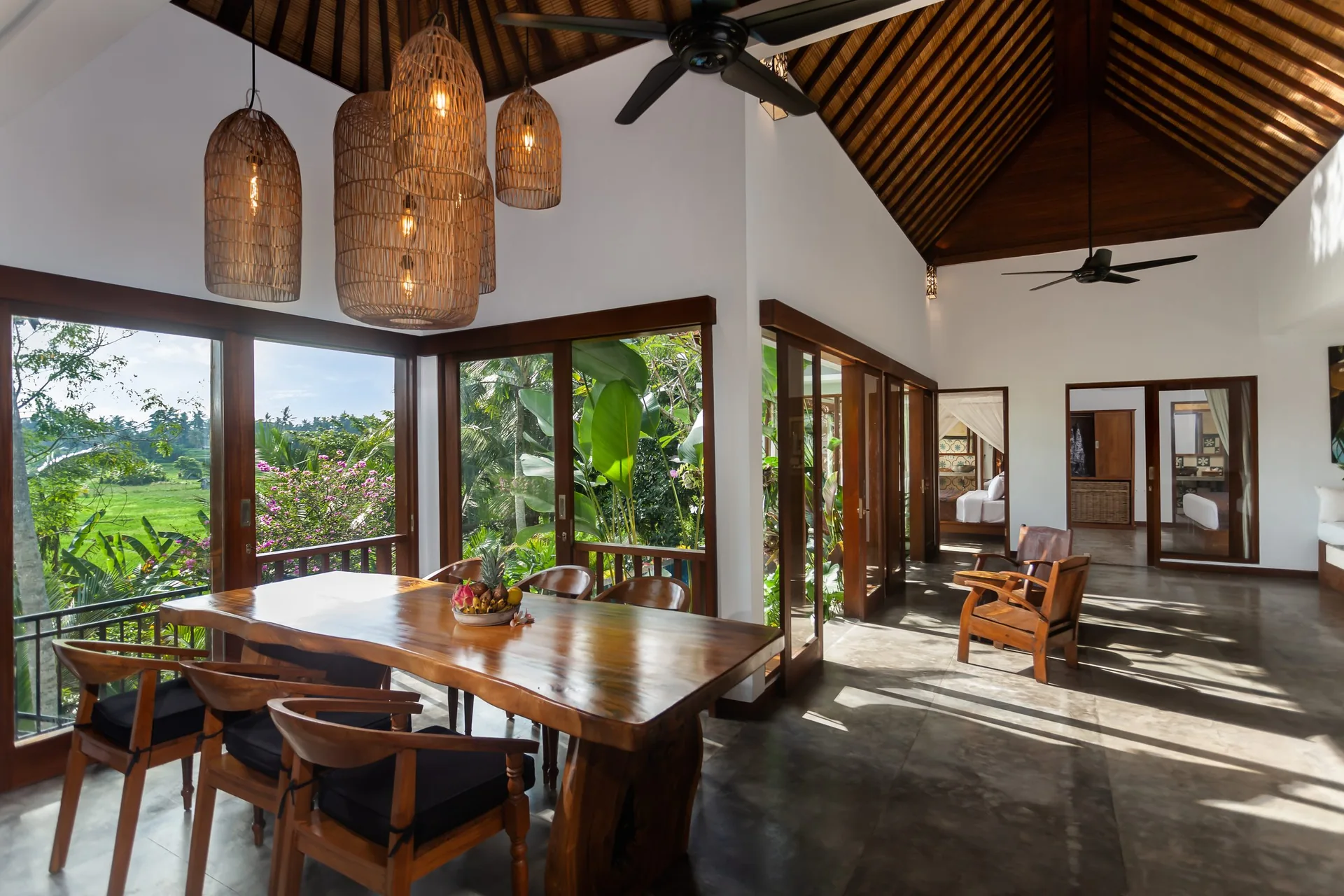 Open living and dining pavilion with a wooden table, pendant lights and rice fields beyond, 2-Bedroom Tranquility Villa at The Shea Ubud